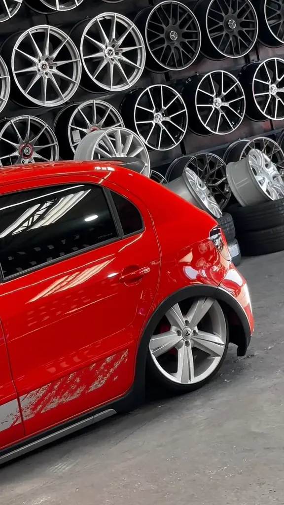 Traseira de um Golf vermelho com a roda recém-montada, ao lado da parede de rodas.